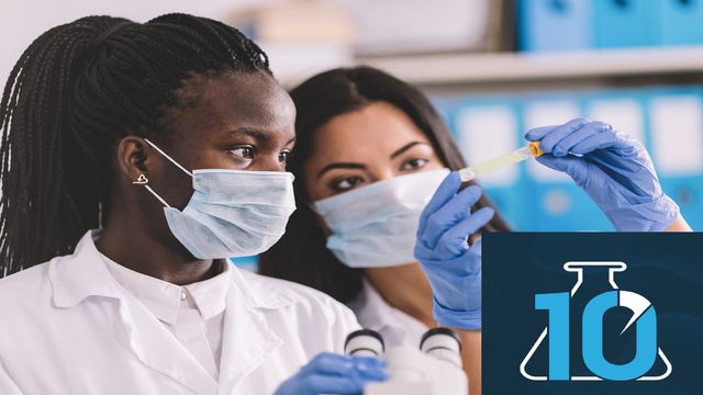 Two female scientists look at a test tube. 