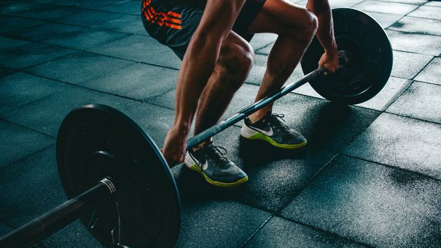 A man deadlifting on grey tiles.  