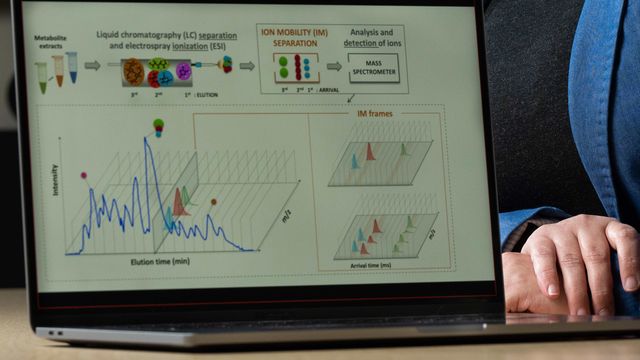 Open laptop with a metabolomics workflow and output displayed on the screen, next to which one of the investigators is seated. 