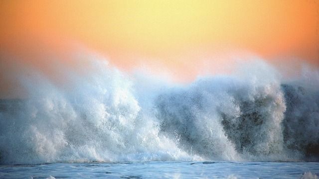 Waves crashing onto the beach and creating lots of aerosol spray. 