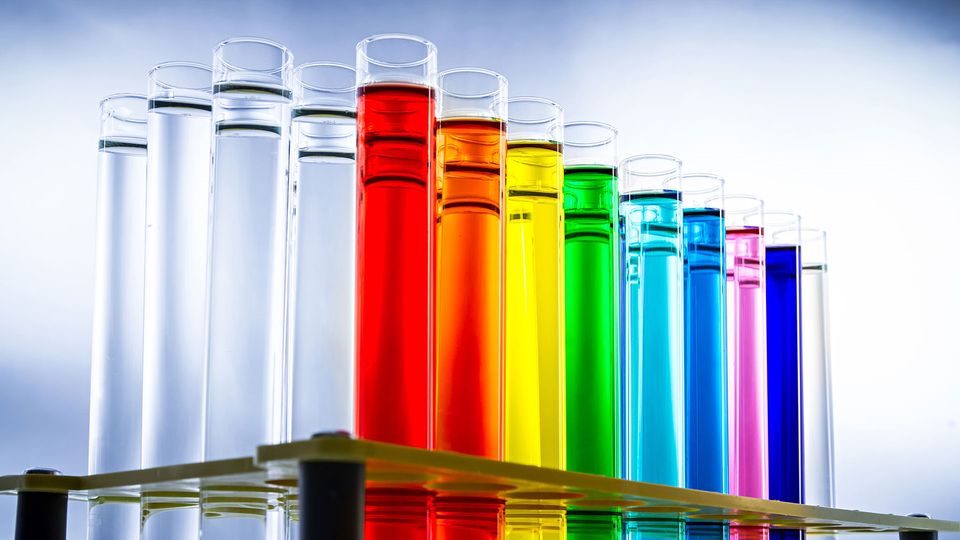 A series of test tubes filled with colored liquid and arranged in a rainbow.