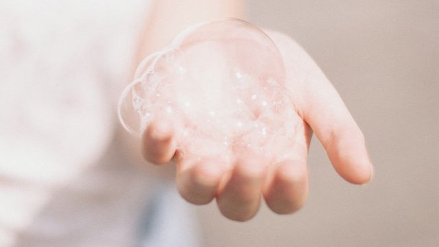 A palm outstretched with soap bubbles on top. 