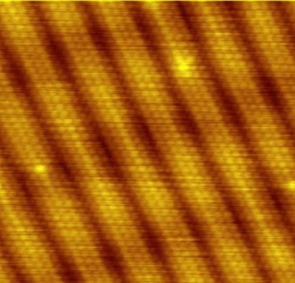 STM image of a gold surface. Individual atoms and their arrangement are directly visible. Dark bands correspond to pits in the surface, with an absence of atoms. 