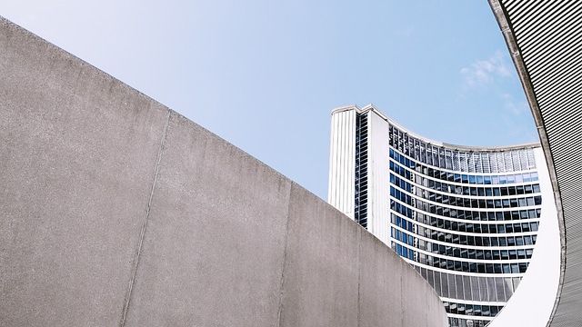 Concrete wall with a curved building in the background. 