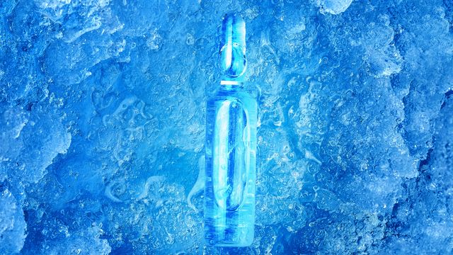 A clear ampule filled with liquid lying on ice. 