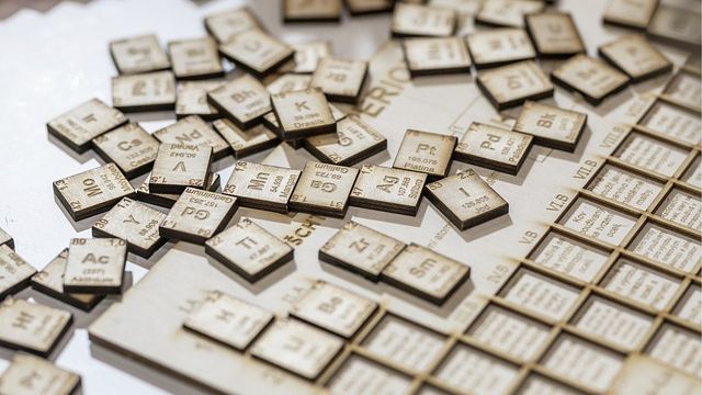 Periodic table jigsaw with all the elements on separate tiles scattered around the table. 